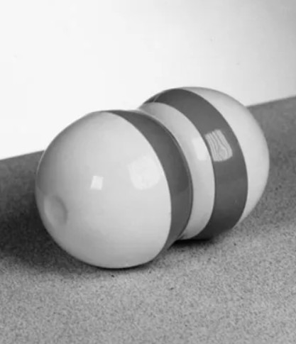 A balck and white photo of a Zerret Applicator - a dumbbell-like plastic object with two darker stripes on its shiny white surface.